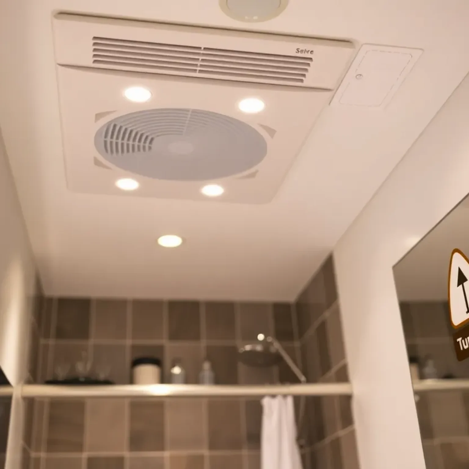 Bathroom with an exhaust fan and a safety warning sign to turn off when not in use.